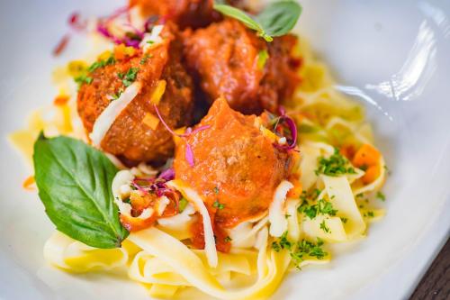 a white plate of food with pasta and meatballs at Le Petit Village Boutique Hotel & Spa in Kampala
