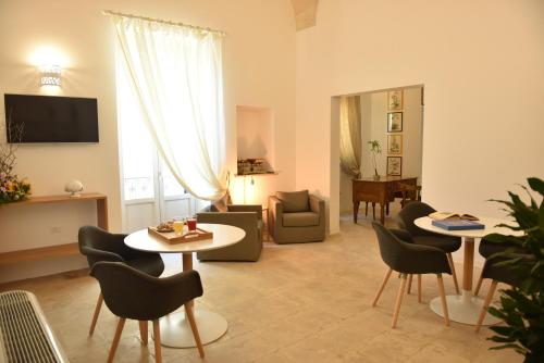 a living room with chairs and tables and a television at Tobacco Suite in Mesagne