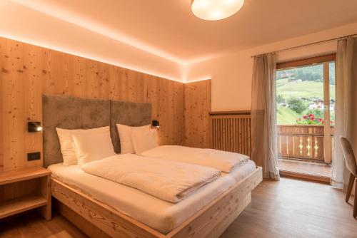 um quarto com uma cama e uma janela grande em Apt Mirko - Haus Kostner em Santa Cristina in Val Gardena