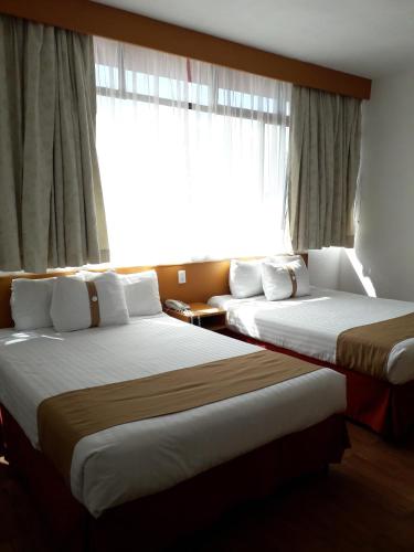 サン・ルイス・ポトシにあるHotel Napolesの窓付きのホテルの部屋にベッドが2つある