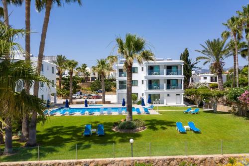 un gran edificio blanco con sillas azules y palmeras en Rododafni Beach Apartments, en Pafos
