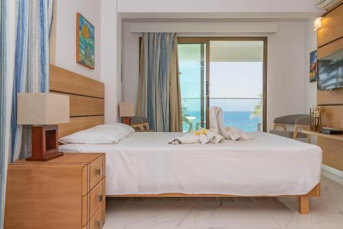 a bedroom with a bed with a view of the ocean at Rododafni Beach Apartments in Paphos City