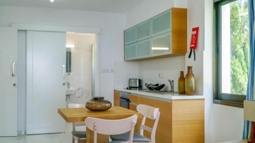 a kitchen with a wooden table and chairs and a sink at Rododafni Beach Apartments in Paphos City