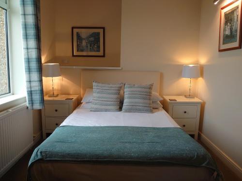 a bedroom with a bed with blue pillows and two lamps at geordie pride lodge in Liversedge