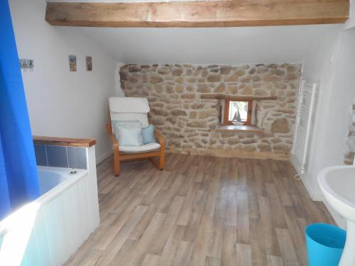 a bathroom with a chair and a stone wall at 38 Friaudour in Saint-Pardoux