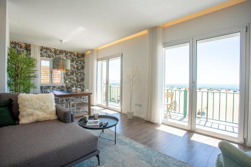 a living room with a couch and large windows at T3 Aleluia in Nazaré