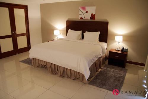 a bedroom with a large bed with white sheets at Ramada by Wyndham Princess Paramaribo in Paramaribo
