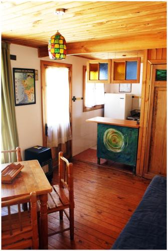 a living room with a table and a kitchen at Cabañas La Magia de Isla Negra in Isla Negra