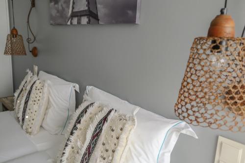 a room with a white couch with pillows and a lamp at Casa da Praça Guest House in Sesimbra