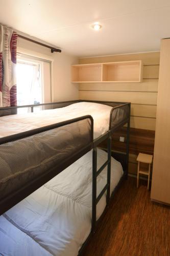 deux lits superposés dans une chambre avec fenêtre dans l'établissement Camping la Palmyre, aux Mathes