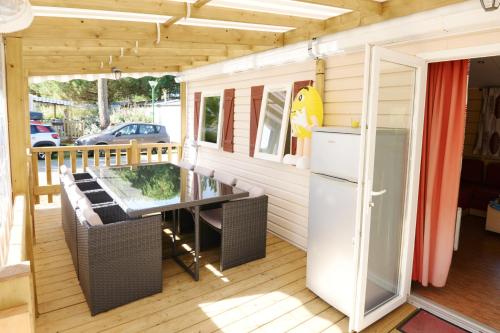 Elle comprend une terrasse couverte avec une table et un réfrigérateur. dans l'établissement Camping la Palmyre, aux Mathes