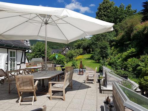 eine Terrasse mit einem Tisch, Stühlen und einem Sonnenschirm in der Unterkunft Ferienwohnung Stickereimuseum Oberhundem in Kirchhundem