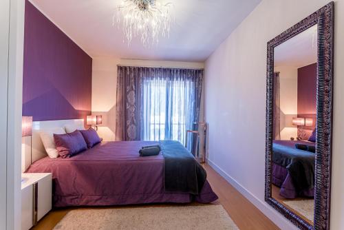 a bedroom with a large purple bed and a mirror at T3 Foz Norte (AL) in Nazaré