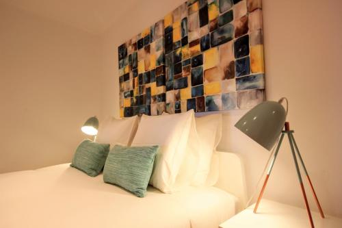 een slaapkamer met een wit bed en een schilderij aan de muur bij Comfort in Old Lisbon in Lissabon