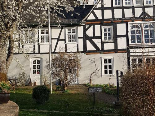 a black and white house with a sign in front of it at Ferienwohnung Stickereimuseum Oberhundem in Kirchhundem