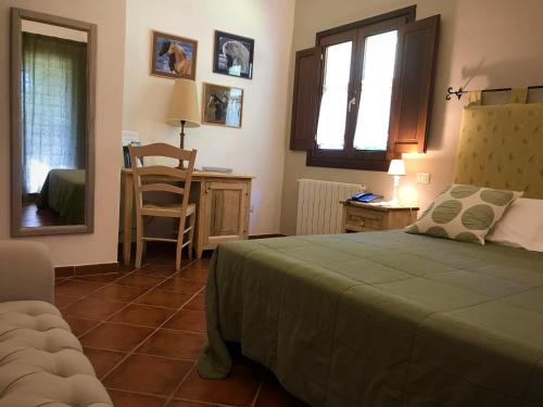a bedroom with a bed and a table and a chair at Tenuta Pilastru Country Resort & Spa in Arzachena