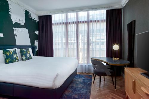 
a bedroom with a bed, chair, desk and a window at NYX Hotel London Holborn by Leonardo Hotels in London
