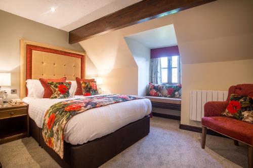 a bedroom with a large bed and a chair at The Bell Inn, Stilton, Cambridgeshire - The Coaching Inn Group in Peterborough