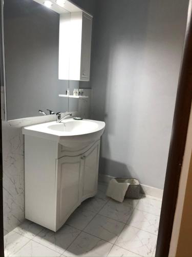 a white bathroom with a sink and a mirror at Casa Maranta in Costinesti
