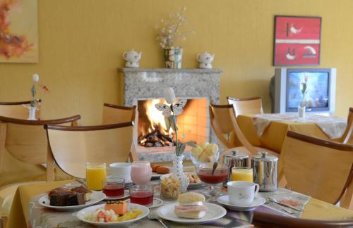 a dining room with a table with food and a fireplace at Pousada Vila das Cores in Campos do Jordão