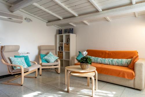 a living room with an orange couch and two chairs at Casa Stella Di Madel in Flumini di Quartu