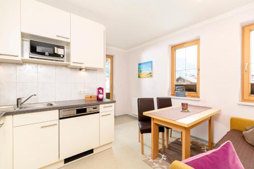 eine Küche, einen Essbereich mit einem Tisch, eine Küche und ein Wohnzimmer in der Unterkunft Apart Heim in Ramsau im Zillertal