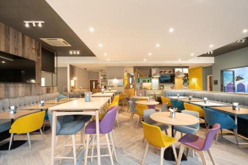 a restaurant with tables and colorful chairs at Holiday Inn Bournemouth by IHG in Bournemouth
