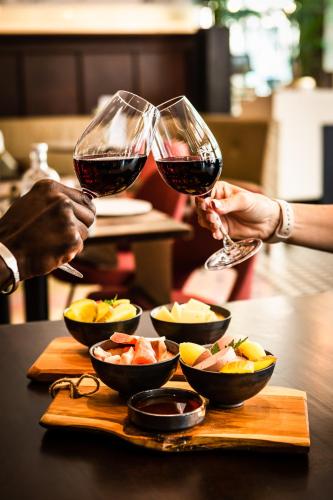 two people are holding glasses of red wine at Hotel Amsterdam De Roode Leeuw in Amsterdam