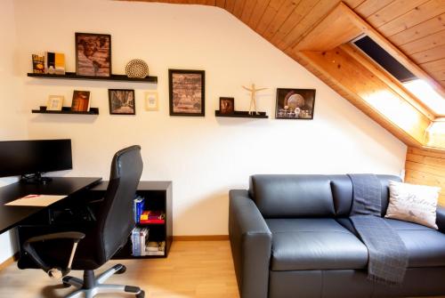 a living room with a couch and a desk and a computer at Armotti Apartments Lorraine in Bern