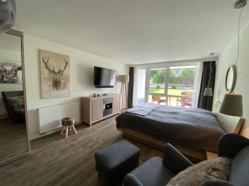 a bedroom with a bed and a tv and a couch at Apartment BERGliebe - schnuckelig, ruhige und zentrale Lage in Schliersee