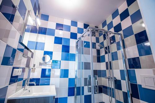 a blue and white tiled bathroom with a shower and a sink at Fred&Breakfast in Ghent