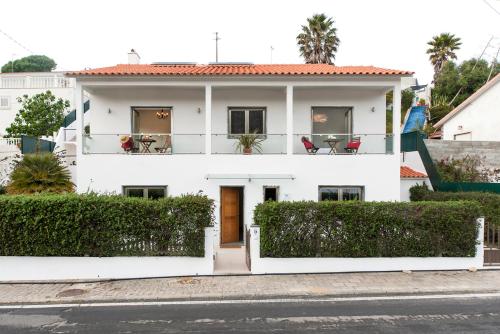 a white house with chairs on a balcony at Beachouse - Surf, Bed & Breakfast in Ericeira