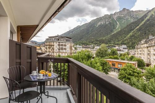 a balcony with a table and chairs and mountains at Pointe Isabelle in Chamonix-Mont-Blanc