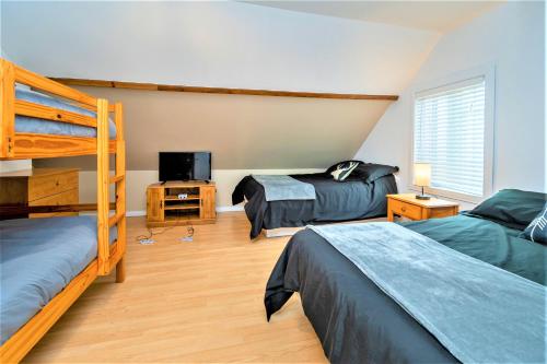 sypialnia z 2 łóżkami piętrowymi i telewizorem w obiekcie Ancestral - Chalet historique w mieście Petite-Rivière-Saint-François
