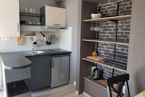 - une cuisine avec un évier et un mur en briques dans l'établissement Appartement centre Avignon, à Avignon