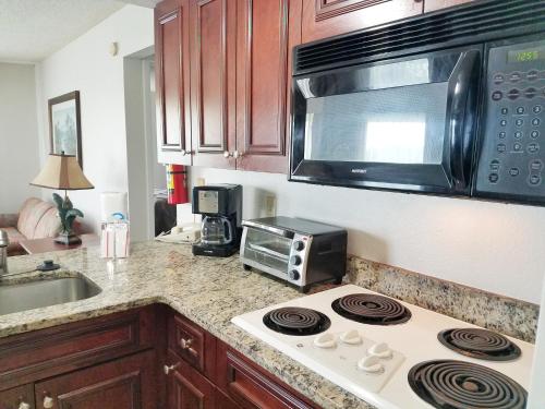 a kitchen with a stove top oven and a microwave at Parc Corniche Condominium Suites in Orlando