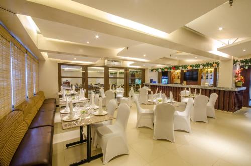 a dining room with white tables and white chairs at Fersal Hotel - Puerto Princesa in Puerto Princesa City
