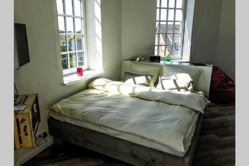 a bed sitting in a room with two windows at Der Wasserturm in Niebüll