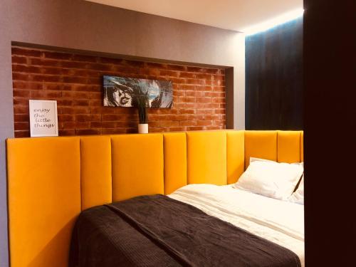 a bed with an orange padded headboard next to a brick wall at GoConcept Studio in Iaşi