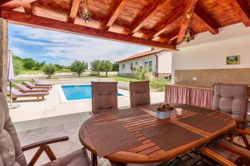 a wooden table and chairs in a room with a pool at Villa Viktoria poll&garden view in Kaštelir