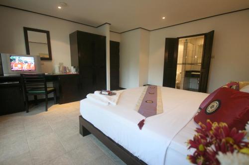 a bedroom with a bed and a desk and a television at Angus O'Tool's Guesthouse in Karon Beach