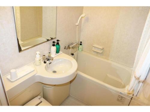 ein kleines Bad mit einem Waschbecken und einer Badewanne in der Unterkunft GRG Hotel Naha - Vacation STAY 86657 in Naha