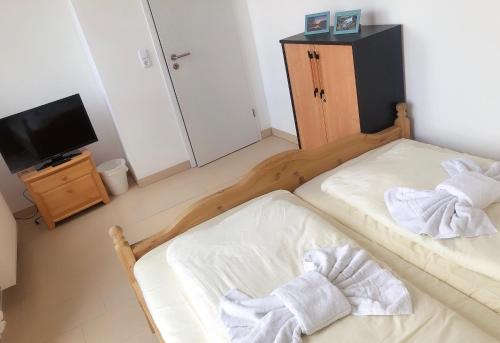 two twin beds in a room with a television at Seehotel Luisenhof in Falkenhagen