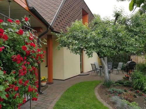 a garden with red flowers and a table and chairs at Helsinkis in Anykščiai