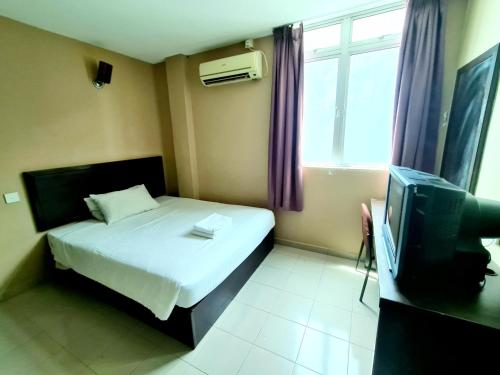 a small bedroom with a bed and a tv at Bee Garden & BB Motel - Alor Setar in Alor Setar
