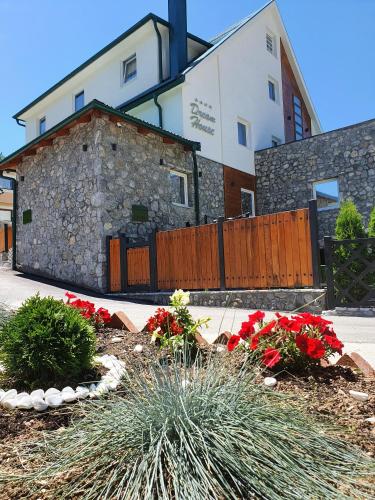 a building with a fence and flowers in front of it at Dream House Hotel & Spa in Kolašin