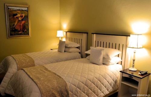 two beds in a hotel room with two lamps at Olive Hill Country Lodge in Bloemfontein