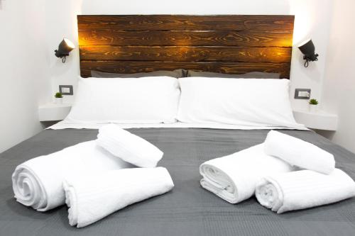 una camera da letto con letto, lenzuola e cuscini bianchi di [Via Dei Tribunali–Duomo] Casina in Centro Storico a Napoli
