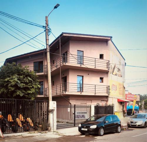a pink building with cars parked in front of it at Casa Maranta in Costinesti