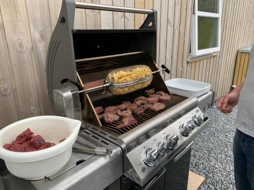 a grill with meat and a bowl of food on it at Lokk-Inn Apartments in Norðdepil